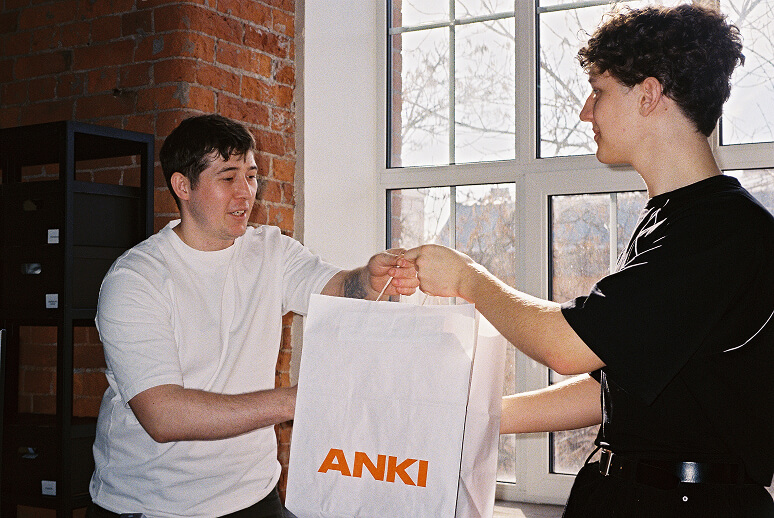 Выдача заказа в шоуруме ANKI: менеджер-консультант передаёт фирменный пакет с кроссовками клиенту