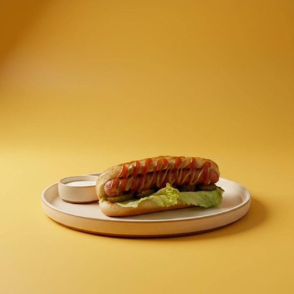 Фуд-фотография хот-дога с кетчупом на желтом фоне. Предметная съемка меню для сервисов доставки еды