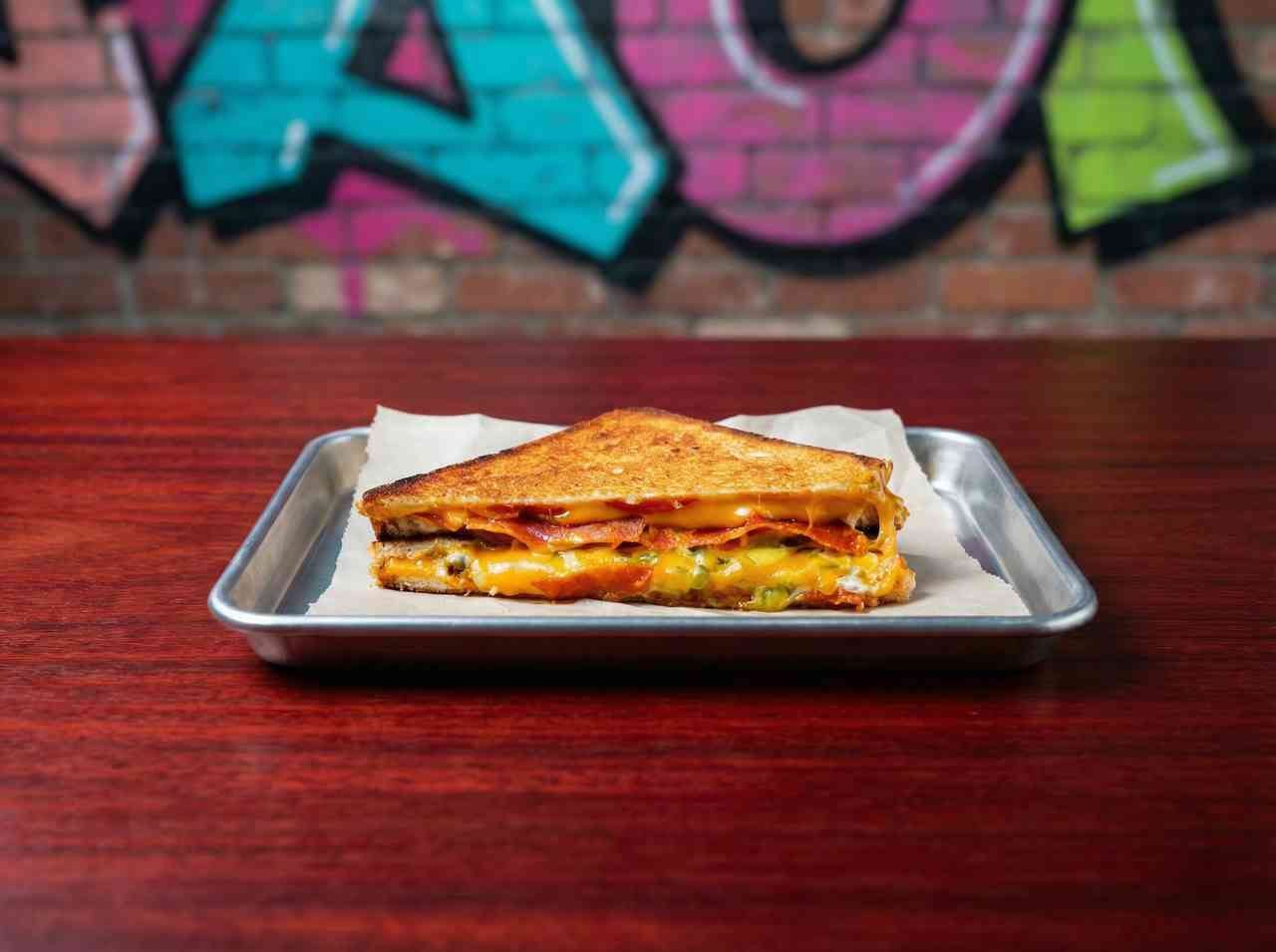 Рекламная фуд-съемка классического сэндвича с ветчиной и сыром. Профессиональное фото быстрого питания в урбанистическом стиле