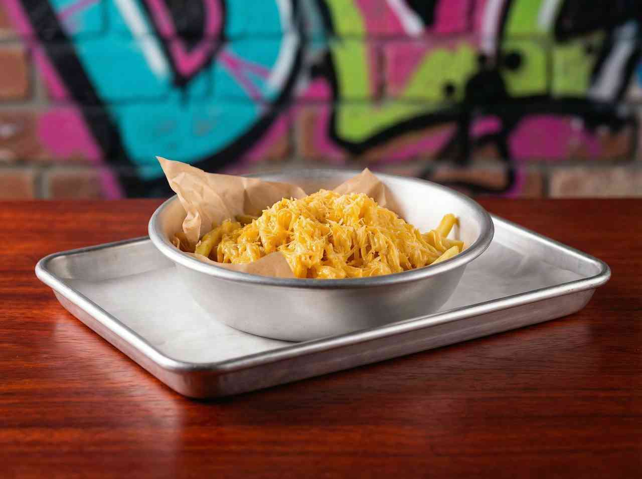 Фуд-фотография сырного блюда мак-н-чиз в металлической миске. Съемка сытных блюд уличной кухни для меню доставки