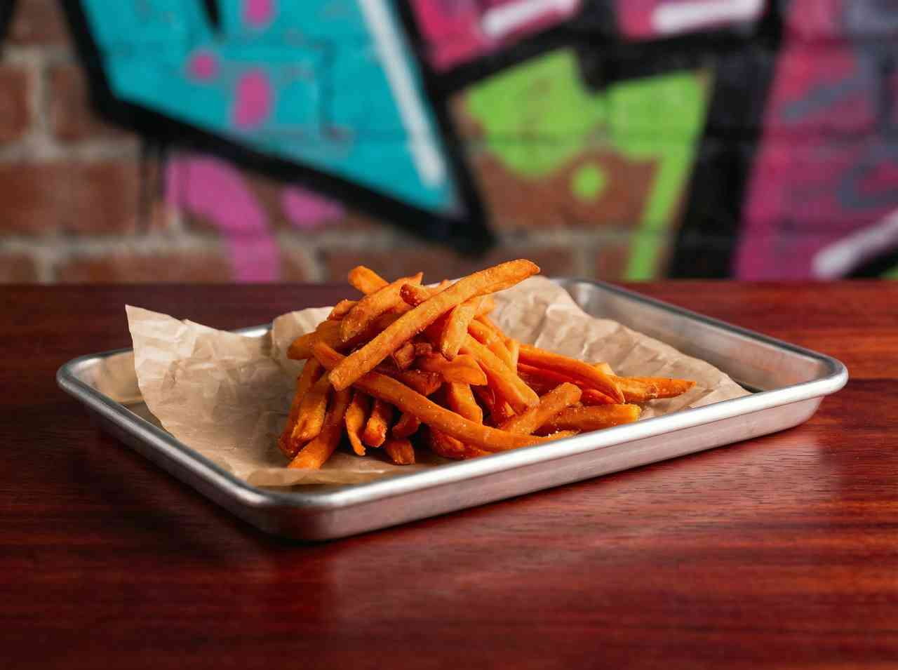 Предметная фуд-съемка батата фри на крафтовой бумаге. Съемка трендовых горячих закусок для меню современного кафе