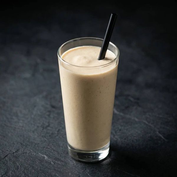 Густой молочный коктейль в высоком стакане. Предметная съемка безалкогольных напитков для меню ресторана