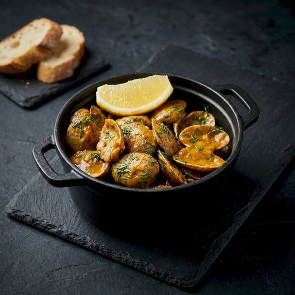 Мидии в раковинах в чугунной кастрюле. Рекламная съемка деликатесов и морепродуктов