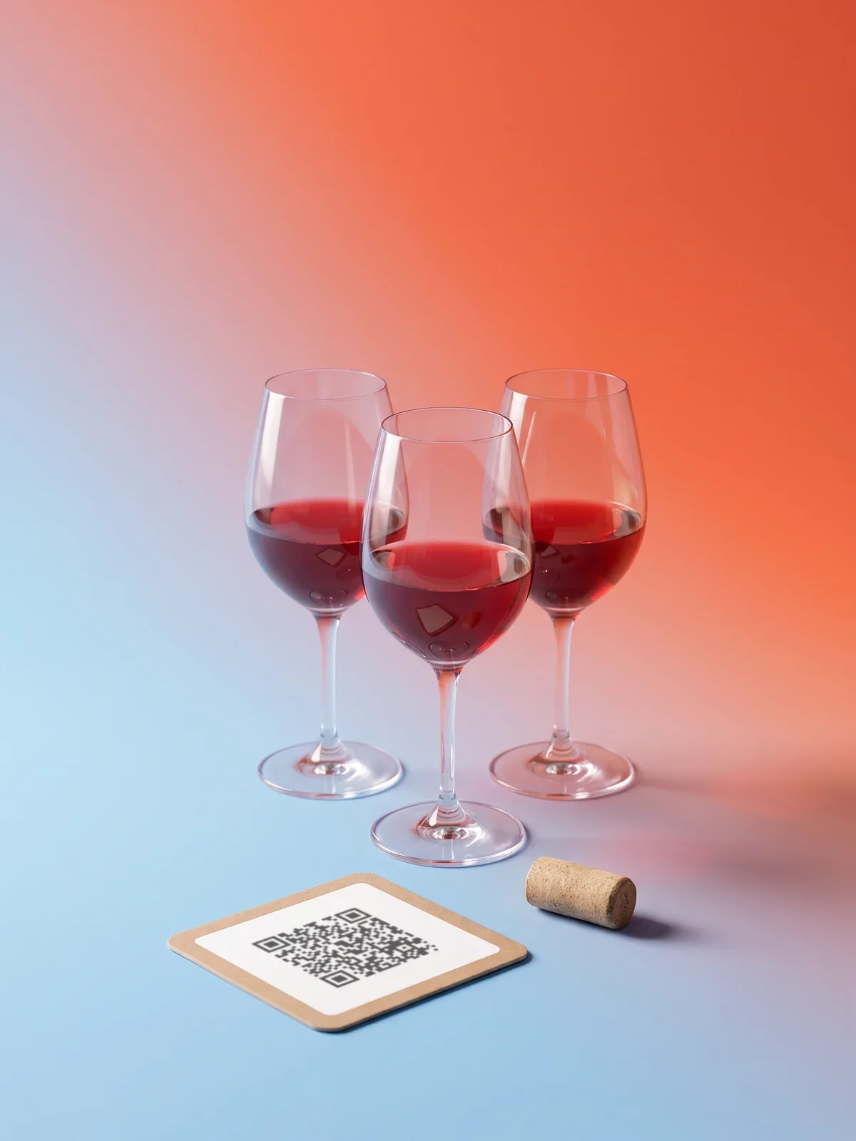 Три бокала красного вина и подставка с QR-кодом на сине-коралловом фоне