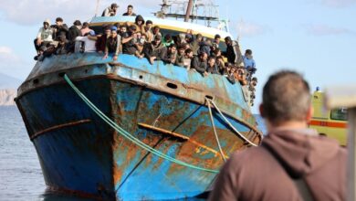 Migrants stand onboard a fishing boat in the port of Paleochora