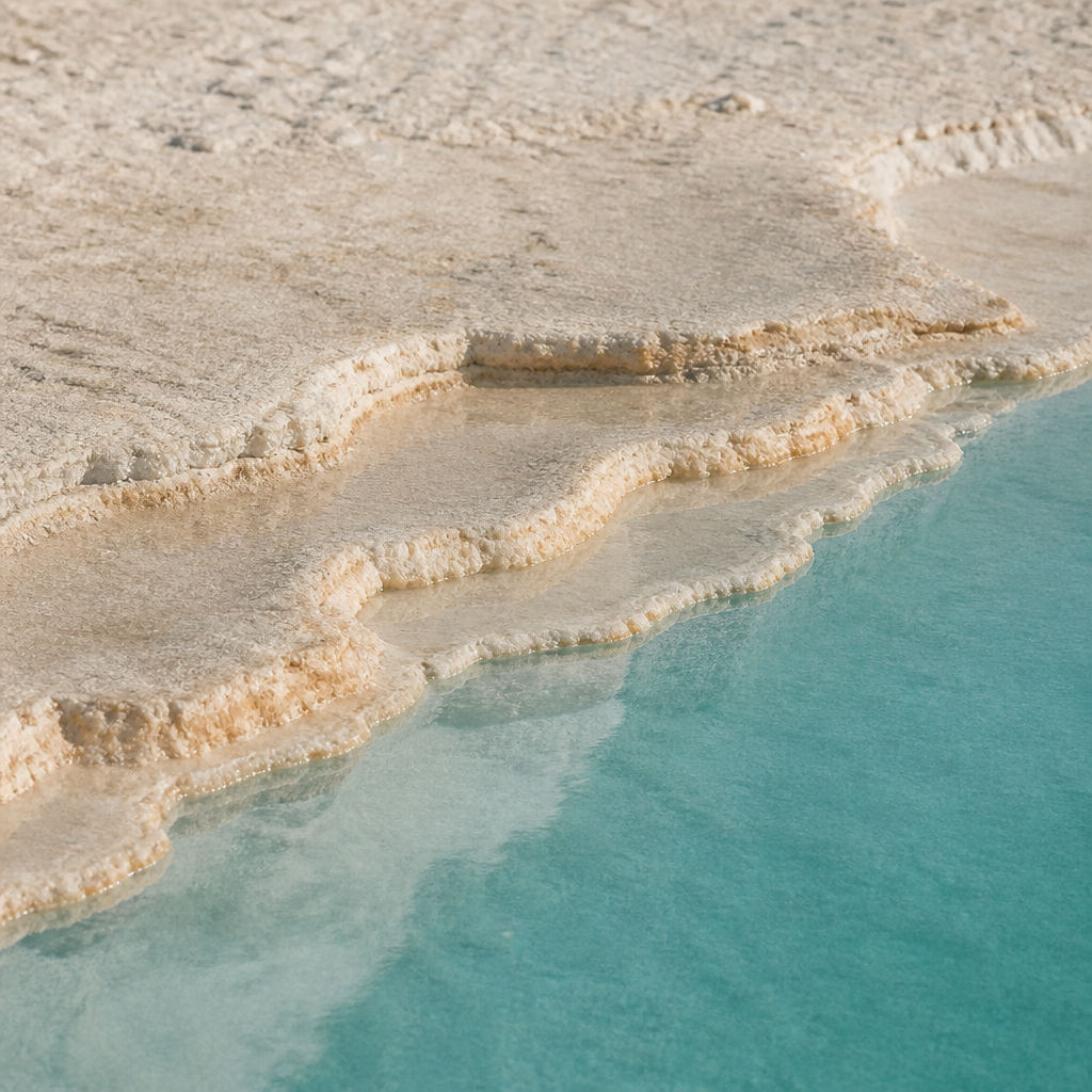 Слоистый край соляной террасы над спокойной бирюзовой водой