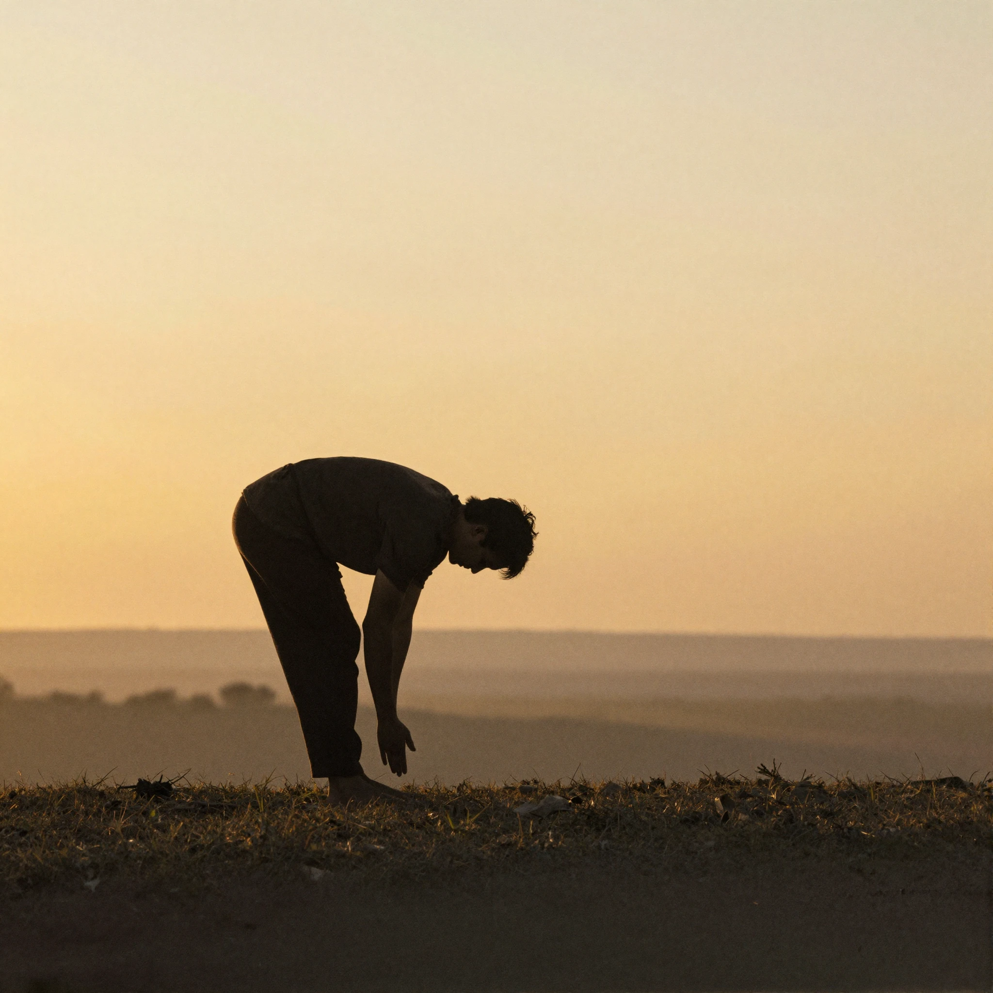 A silhouette of a person bowing deeply to the earth in the f...