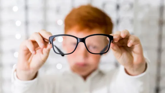 close-up-boy-showing-black-frame-eyeglasses-optics-shop-v1