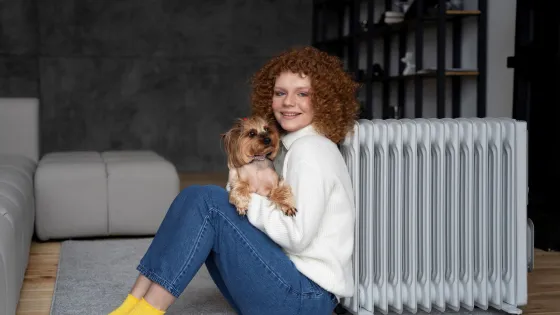 full-shot-woman-sitting-near-heater-with-dog-v1