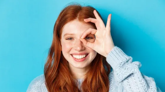 headshot-cheerful-redhead-female-model-showing-okay-sign-eye-smiling-satisfied-happy-standing-against-blue-background_1258-56293-v1