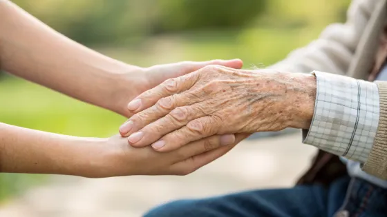 a-young-hand-holds-the-hand-of-an-elderly-man-in-c