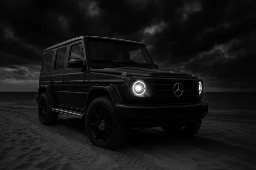 Черный Mercedes G-Class стоит на песчаном пляже под облачным небом