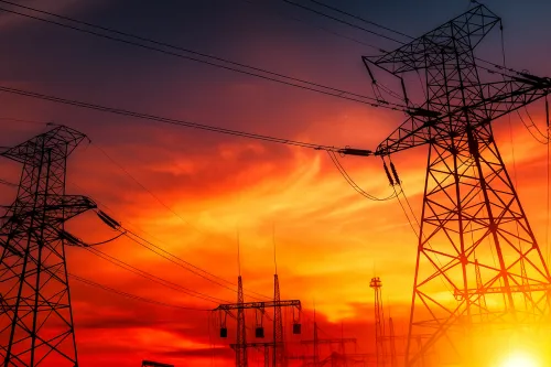 Silhouetas de torres eléctricas frente a un cielo brillante al atardecer