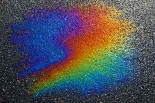 Bright colors of the rainbow blurred on gray asphalt after rain