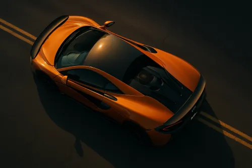 Orange McLaren on an asphalt road under sunlight