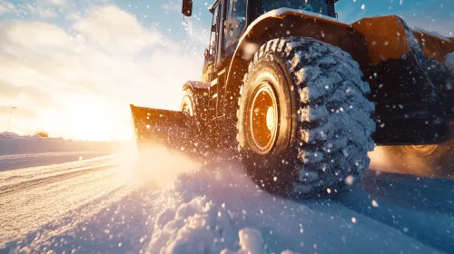 El tractor limpia el camino invernal de nieve bajo un brillante sol