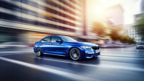 Blue BMW car speeding down a city street with a blurred background