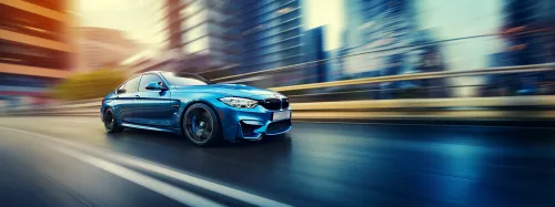 Coche deportivo azul BMW acelerando por las calles de una ciudad moderna