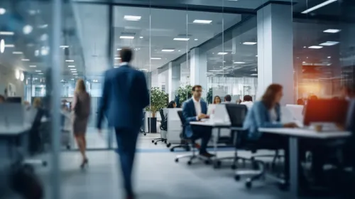 Image of a modern office space with employees working and glass partitions