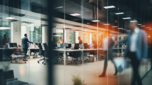 Image of an office with busy employees and workspaces