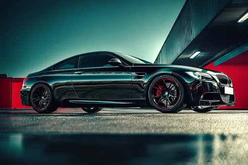Black sports coupe with red wheels in a covered parking lot