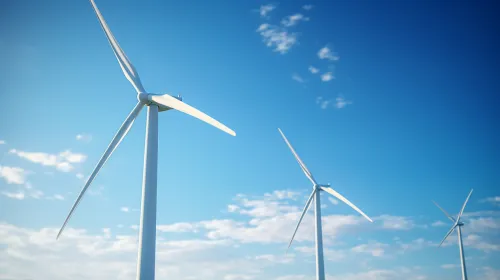 Modern wind turbines against a backdrop of blue sky and clouds