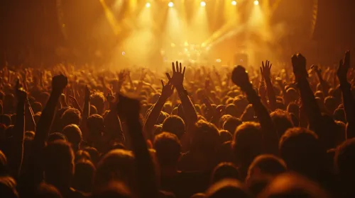 Multitud de personas con las manos levantadas en un concierto musical, luces brillantes