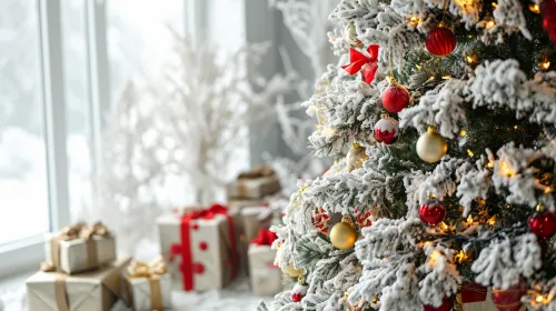Snowy tree decorated with ornaments and gifts against a winter landscape
