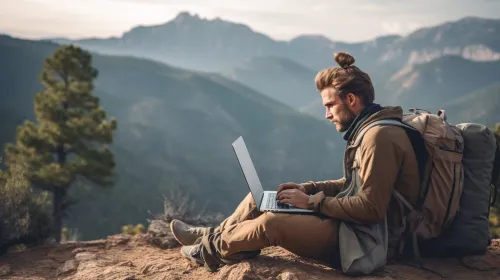 Paisaje montañoso con una persona trabajando en una computadora portátil en la naturaleza