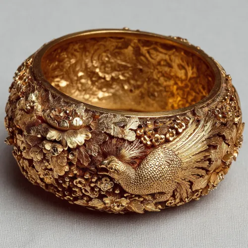 Exquisite golden bracelet with detailed reliefs of flowers and a bird