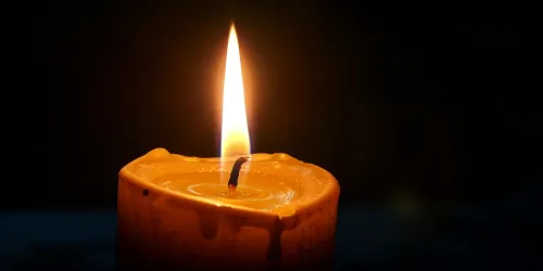 Lone candle with bright flame on dark background