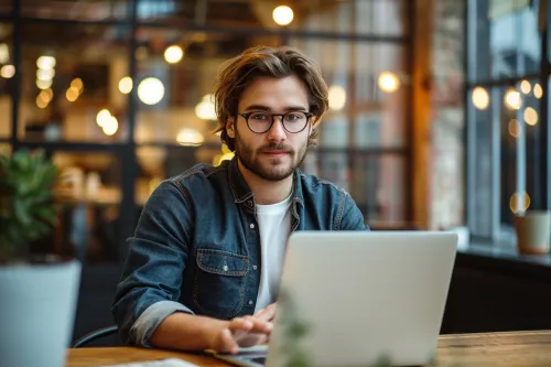 Portrait of a young man working on a laptop in a cozy café
