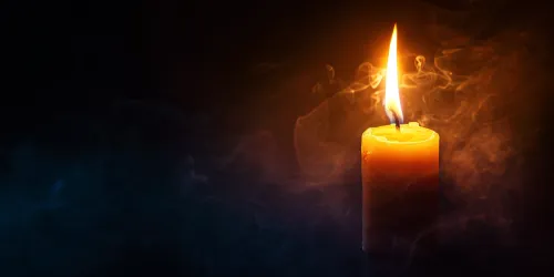 Burning candle with smoke on a black background