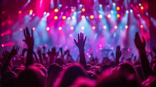 Multitud de personas en un concierto con las manos en alto y luces brillantes