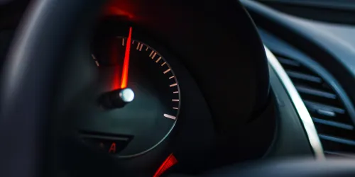 The image shows a speedometer, with a red needle in focus