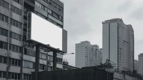 Billboard vacío entre edificios grises bajo un cielo nublado