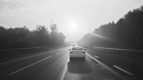 Coche blanco en una carretera vacía envuelta en niebla y suave luz