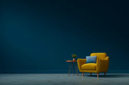 Bright yellow armchair next to a round table against a dark wall