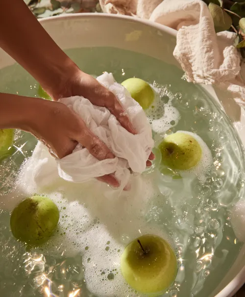 The process of washing green apples in a water bath with soap bubbles