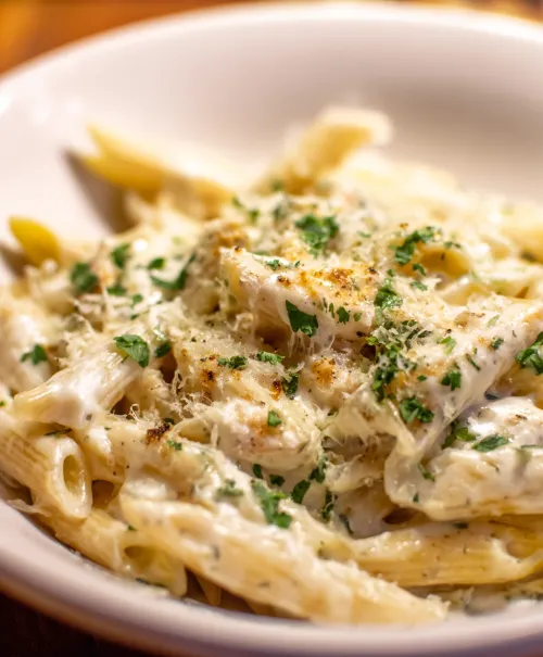 Penne pasta in creamy sauce with parsley and grated cheese