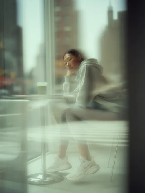 Image of a young woman in a gray hoodie sitting at a table in a café