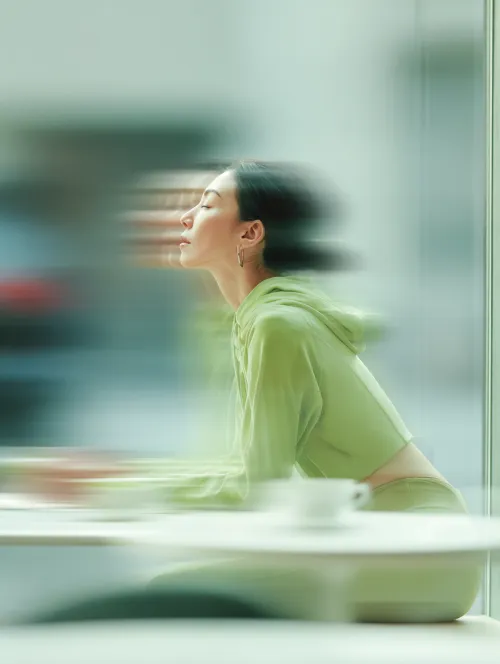 Image of a woman in green sitting in a cafe with blurred motion