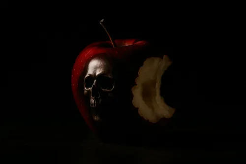 Manzana oscura con la imagen de una calavera y un lado mordido