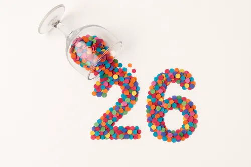 Цветной круглый конфетти, образующие цифры 26, перевернутый бокал