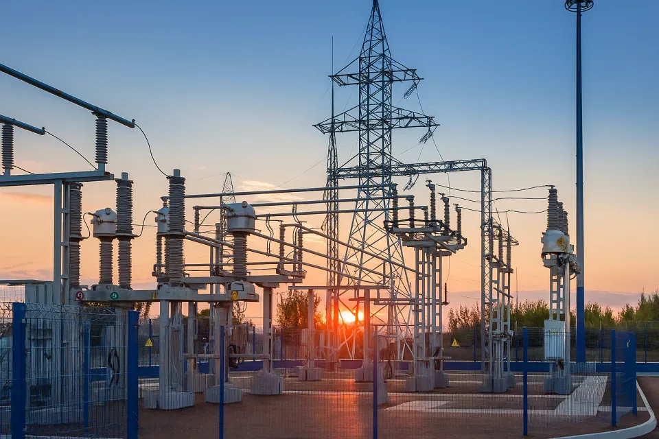 Subestación con líneas de alta tensión y postes al atardecer