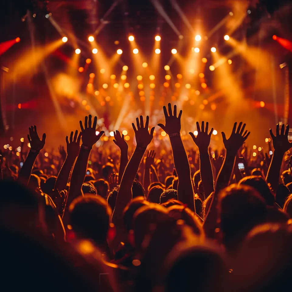 Multitud en un concierto con las manos levantadas y luces brillantes