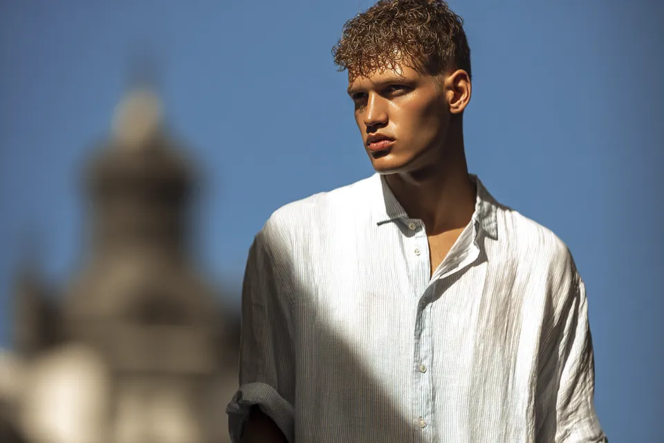 The eyes of a young man with short light brown hair, dressed in a light shirt