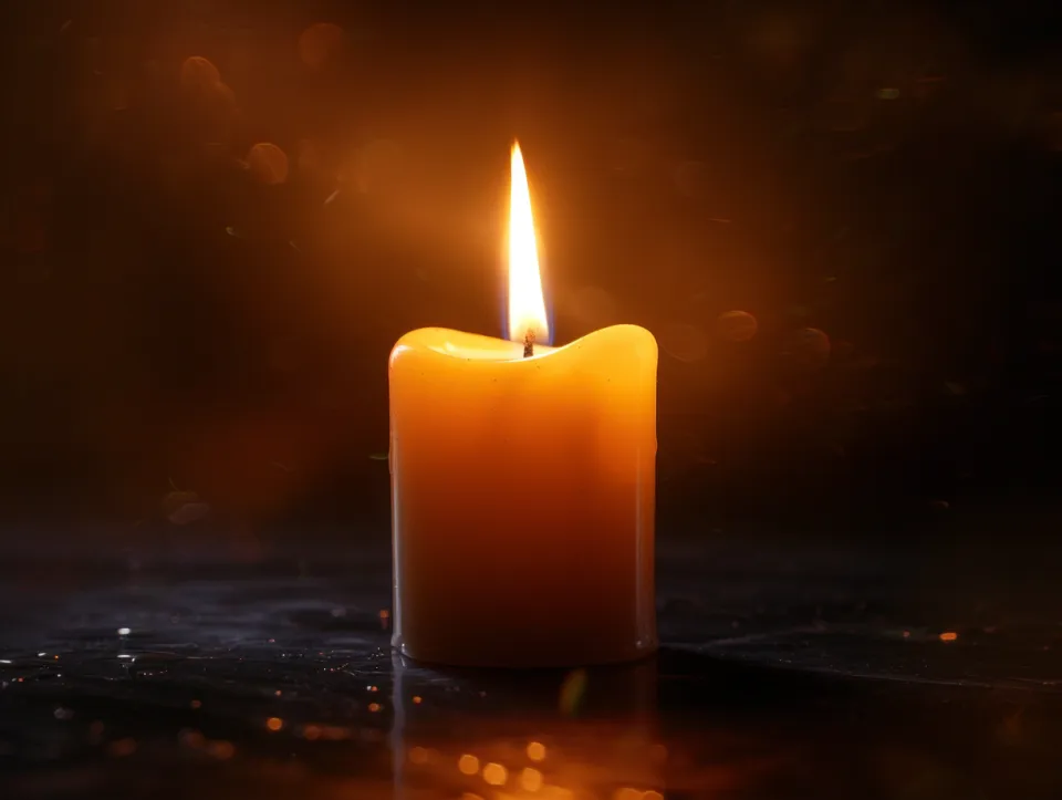 Lit candle with a soft glow against a dark background