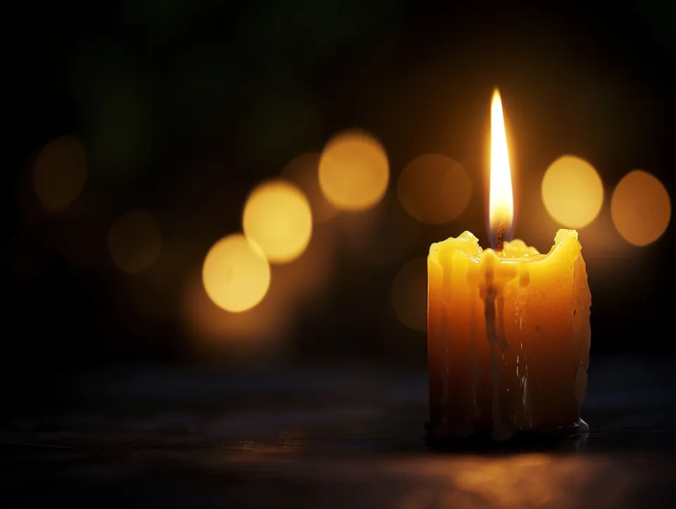 Vela con luz cálida sobre un fondo de luces difusas