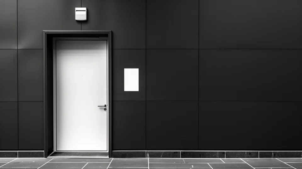 White door against a textured black wall with a white sign
